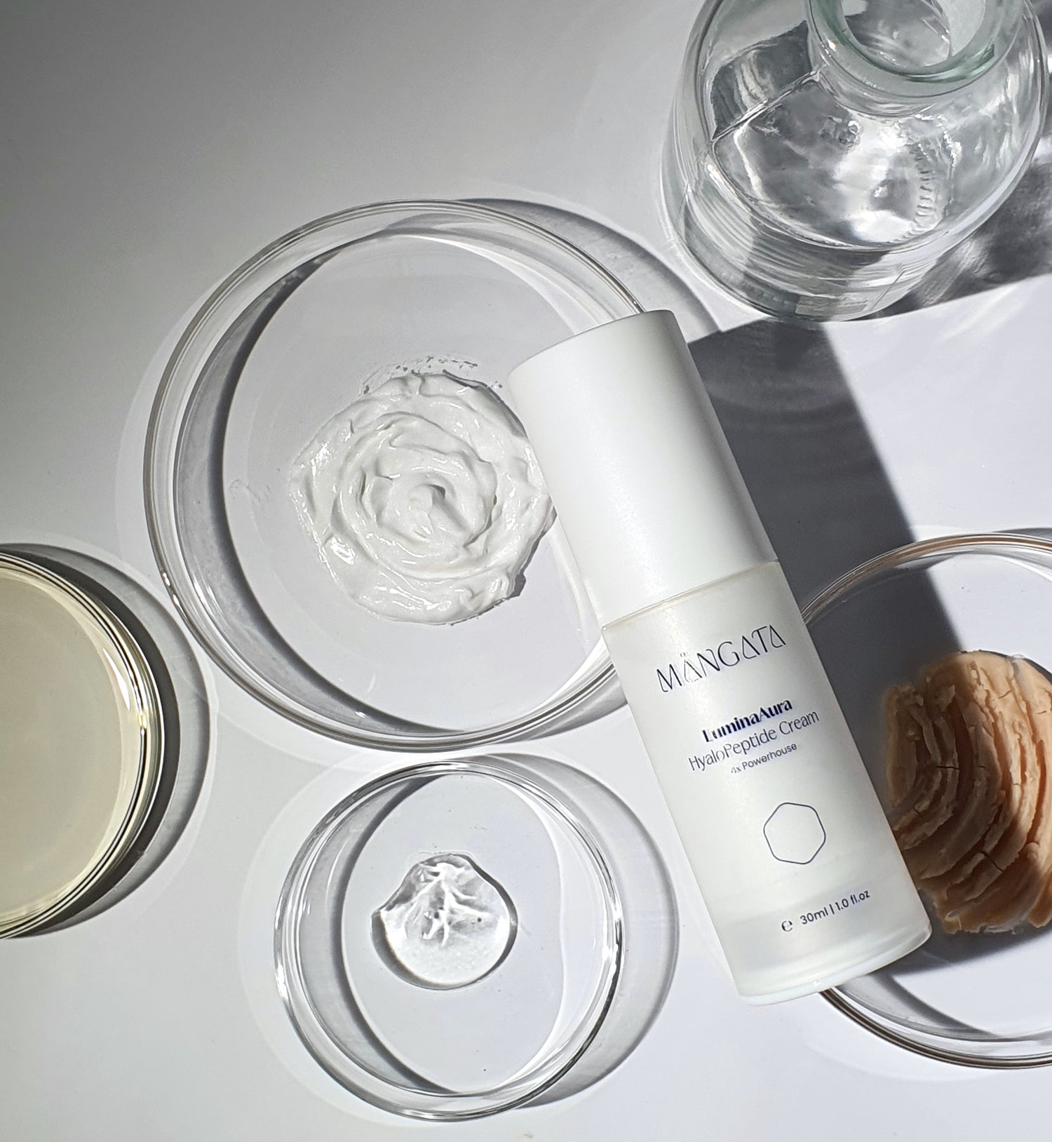 Elegant cream bottle lying on petri dishes filled with various raw materials and natural ingredients.