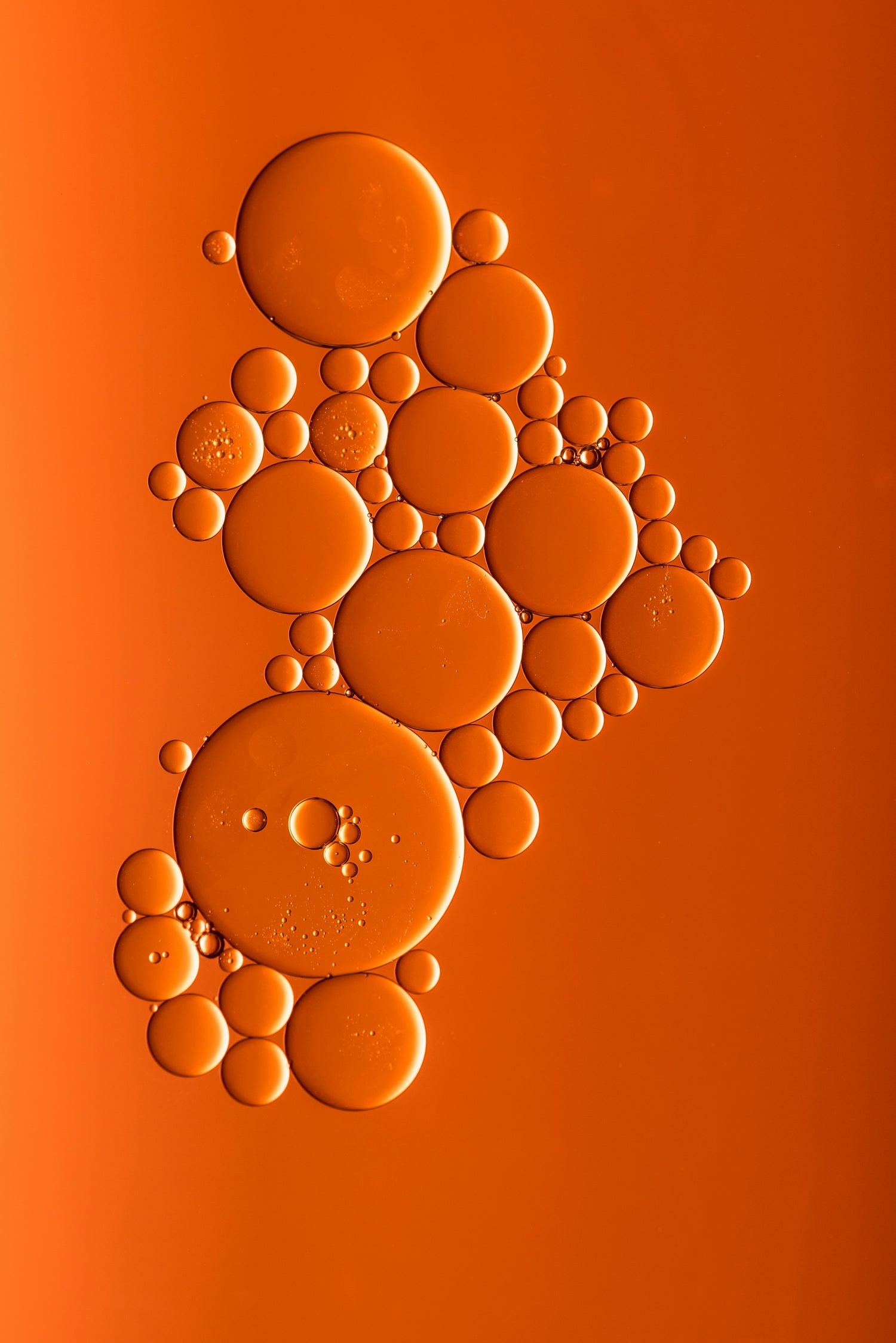 Microscopic view of oil droplets on a dark orange background, showcasing intricate details and texture.